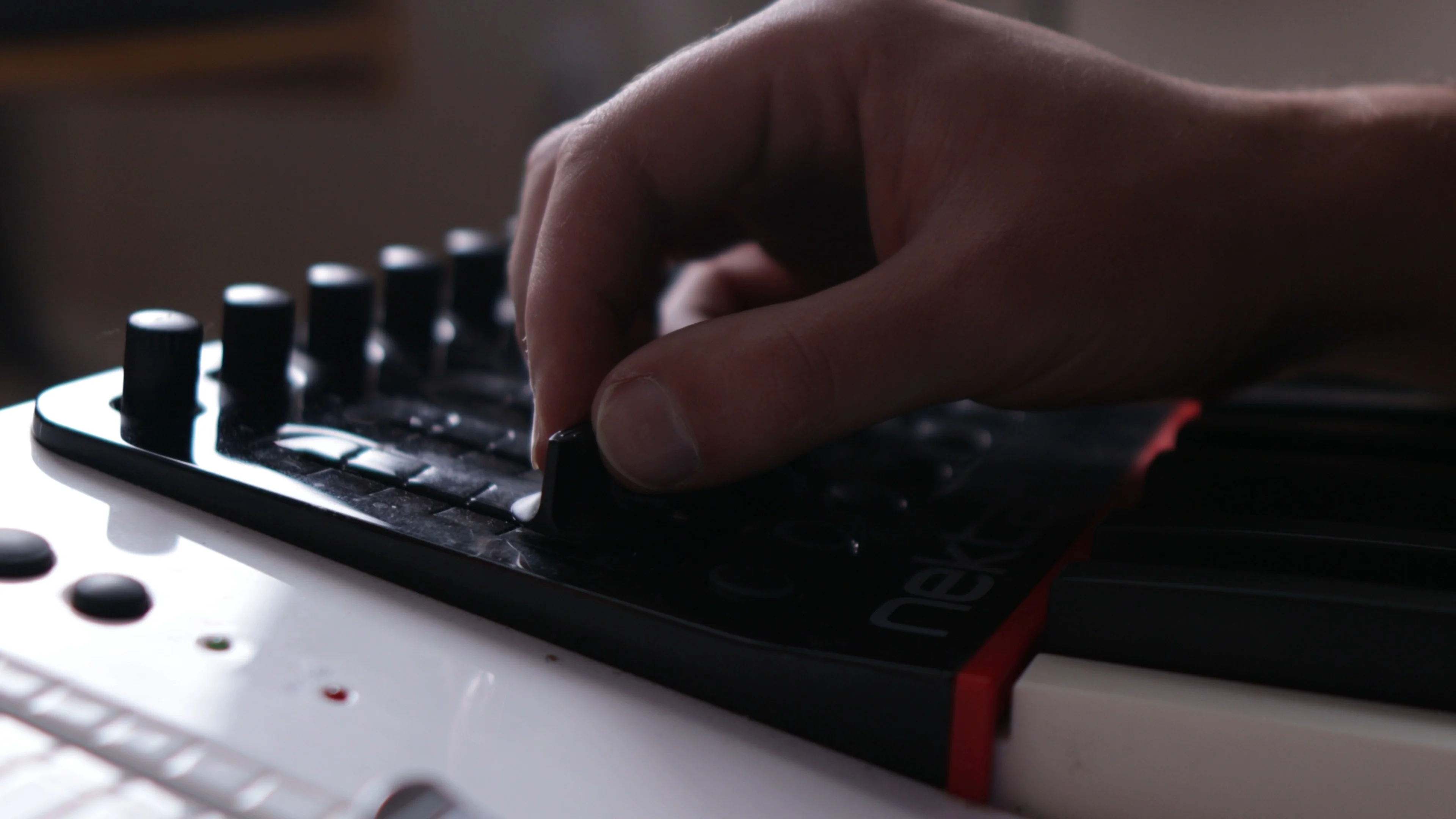 Mattie adjusting MIDI controller knobs to program AI-generated chord progressions and melodies