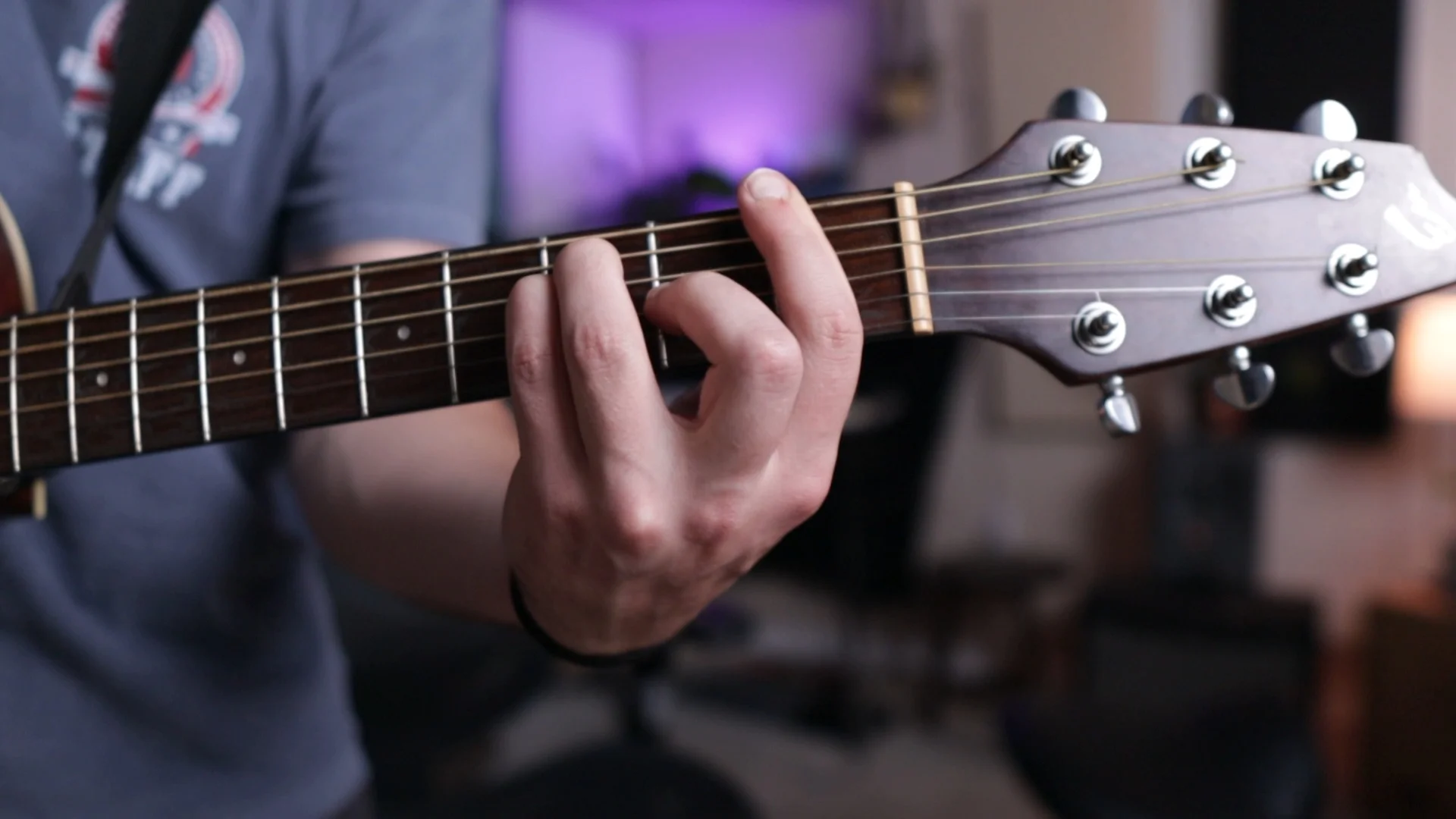 Mattie demonstrating chord fingering positions on acoustic guitar, showing proper hand placement for learning the four-chord progression