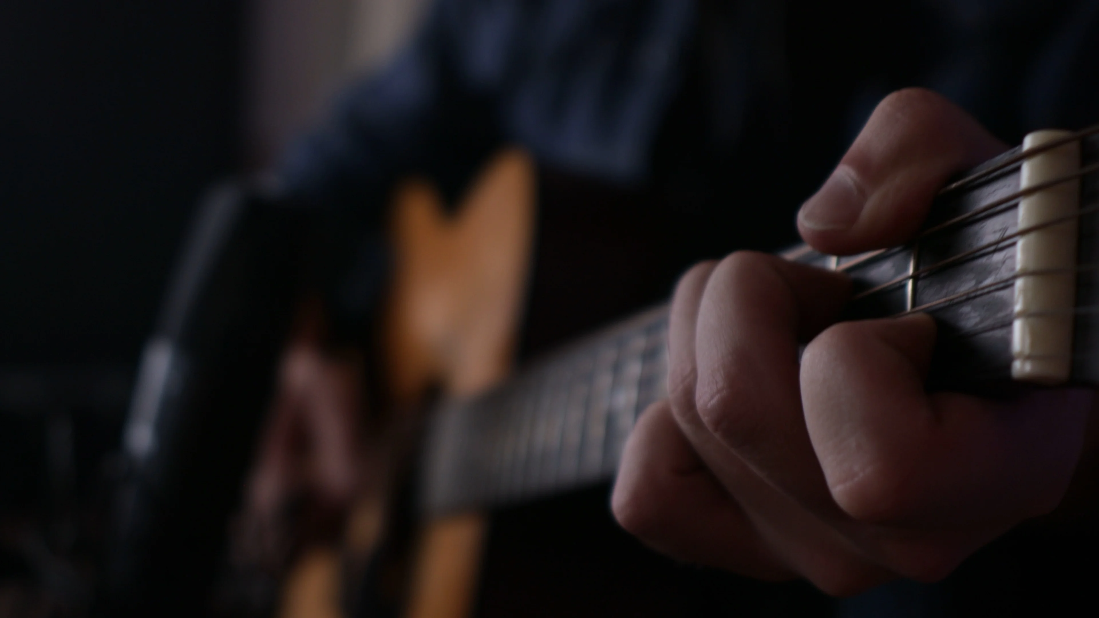 Close-up of hands playing acoustic guitar chords, demonstrating the foundational elements that make up a song's verse structure