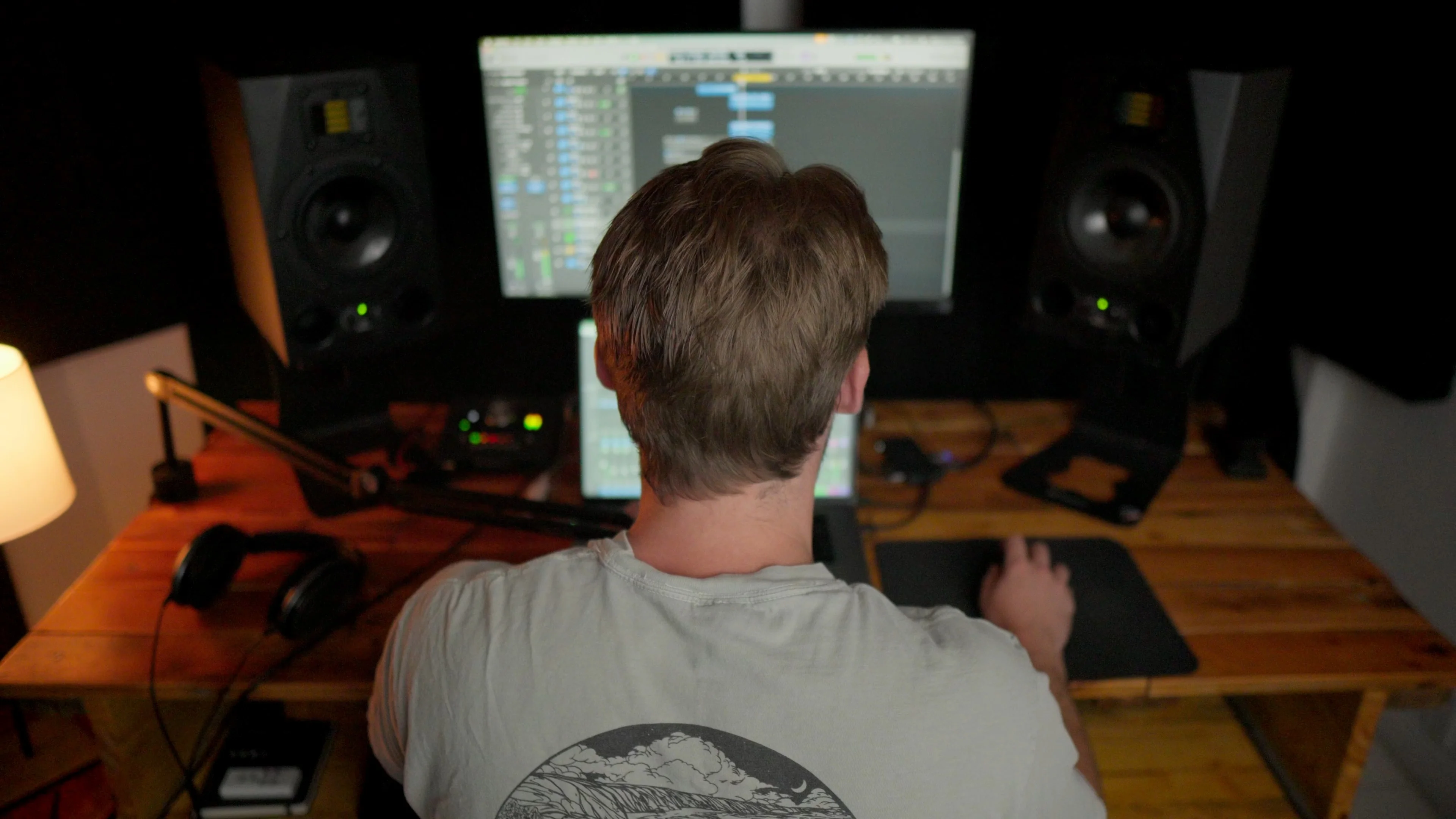 Mattie working at home studio setup with Logic Pro displayed on screen alongside professional studio monitor speakers