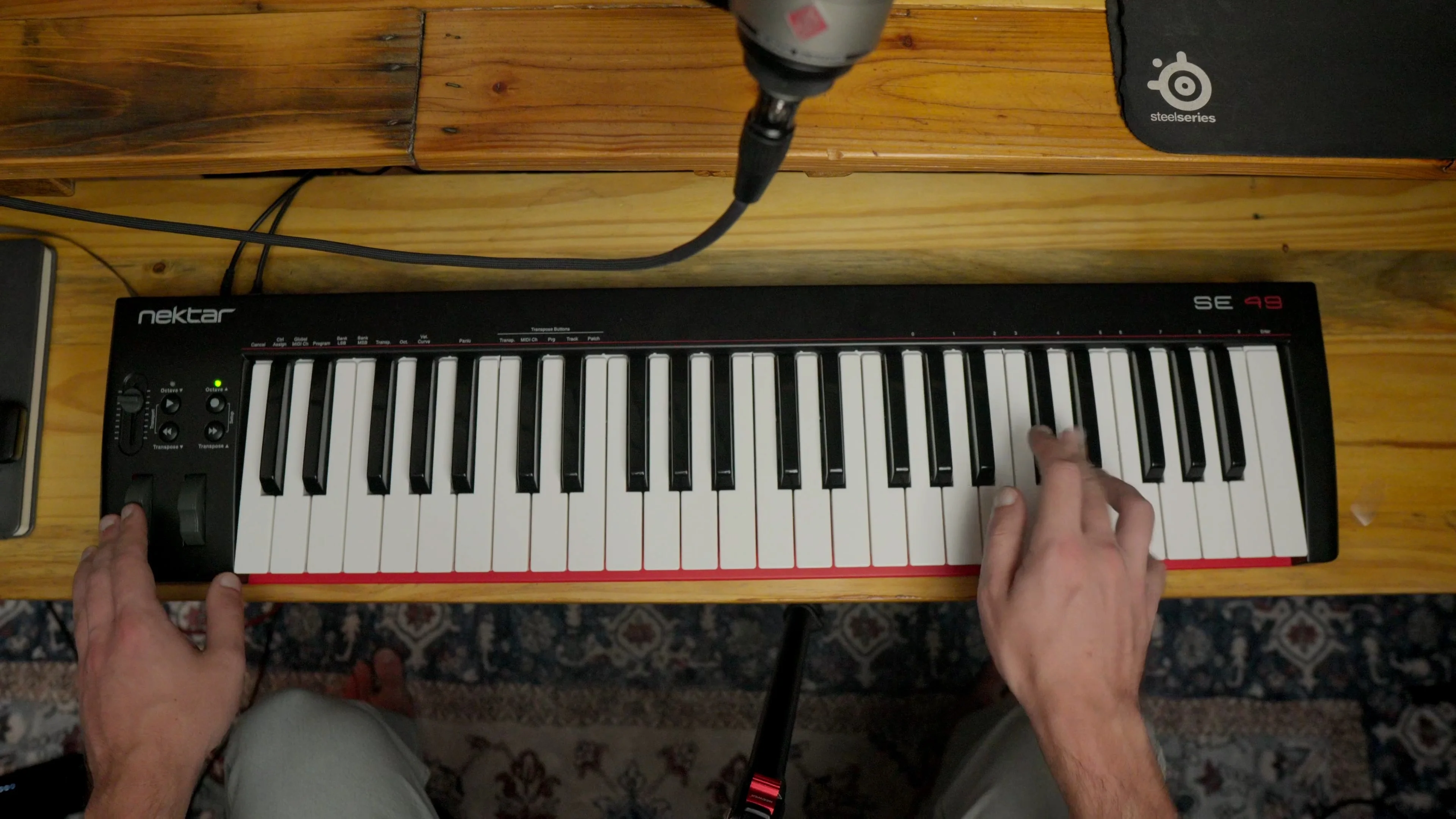 Top-down view of hands playing MIDI keyboard controller, representing the intersection of human creativity and AI music production technology