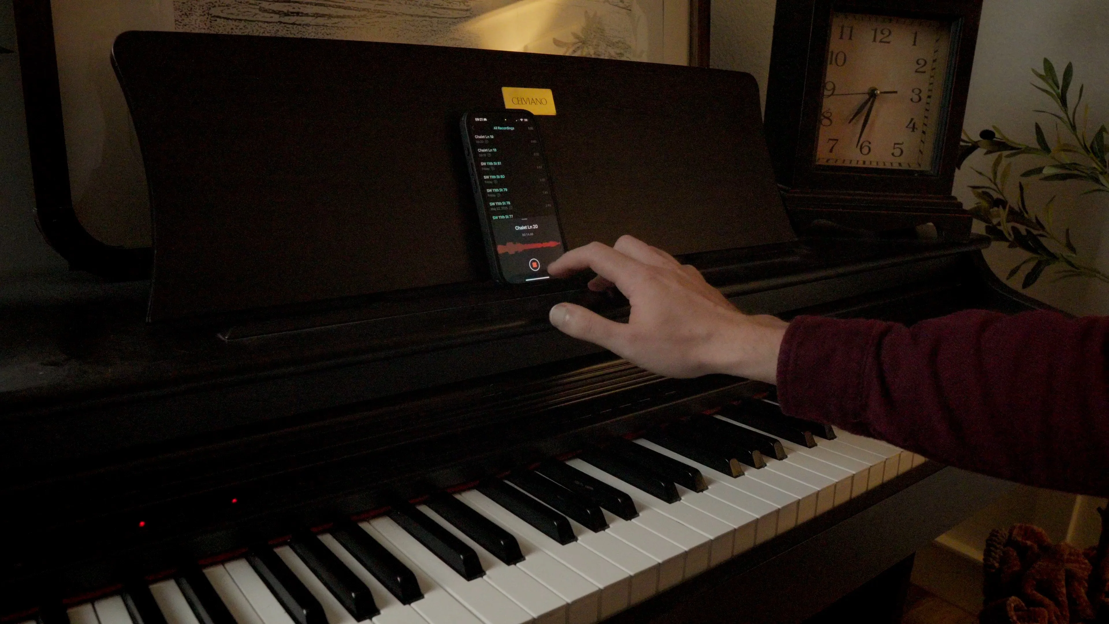 Mattie using smartphone at piano keyboard for recording songwriting ideas, demonstrating integration of digital tools with music creation