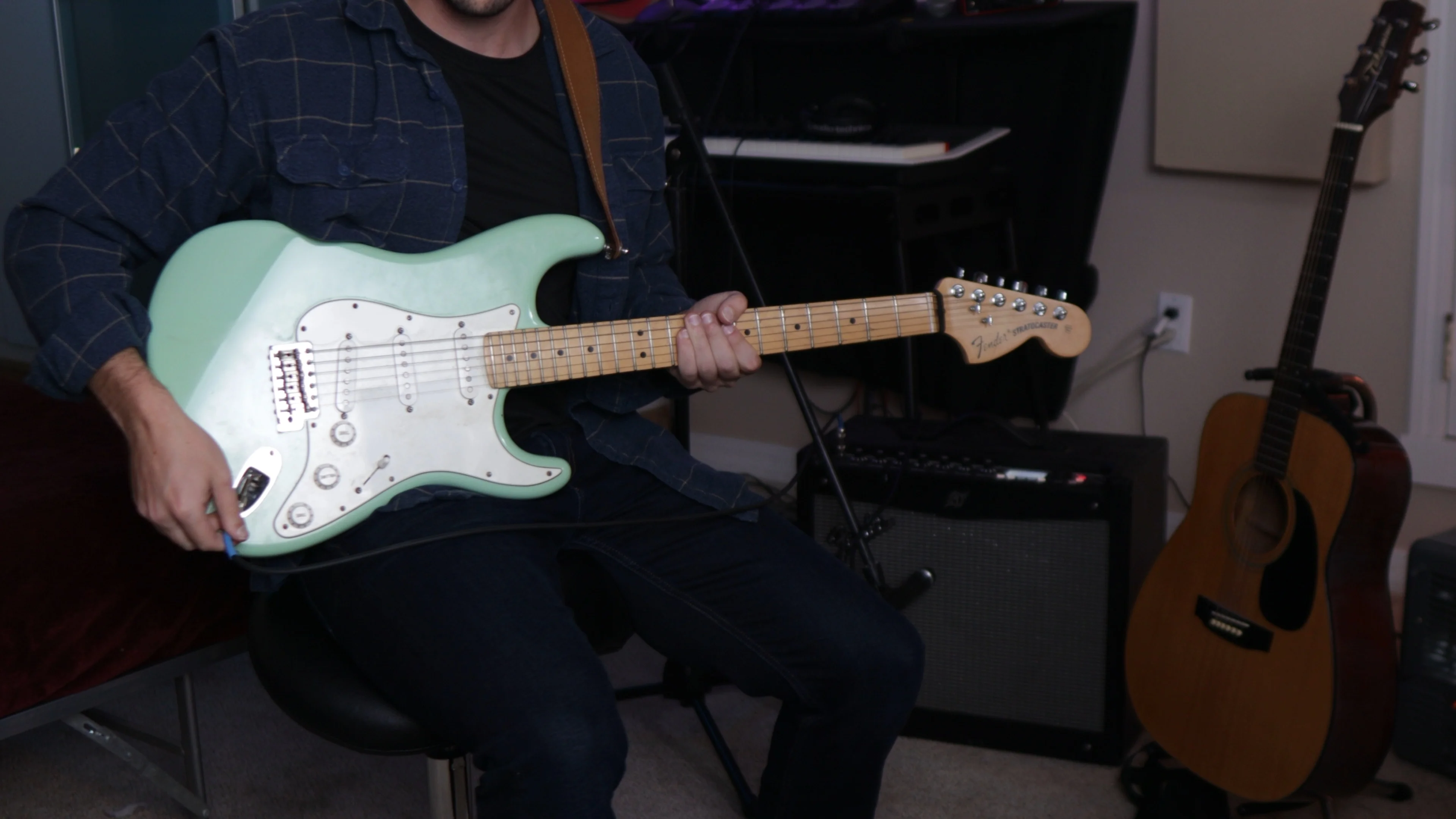 Mattie playing electric guitar in home studio, demonstrating guitar amp processing techniques used in The Strokes' signature sound