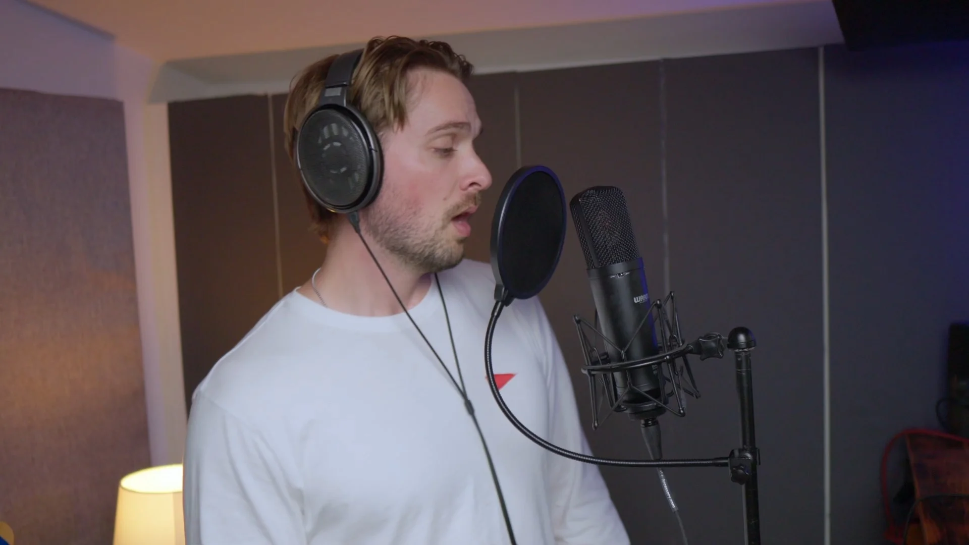 Mattie recording vocals with condenser microphone in DIY vocal booth, demonstrating proper microphone positioning for crowd chant recording