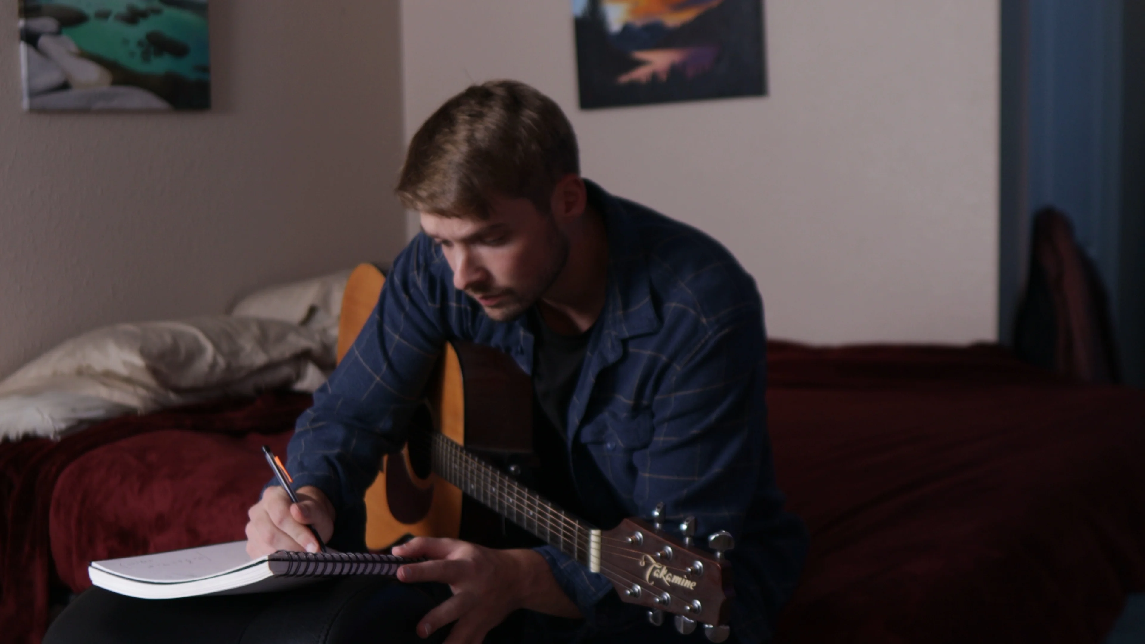 Mattie composing songs with acoustic guitar and notebook, testing creative instincts against scientific hit-making formulas