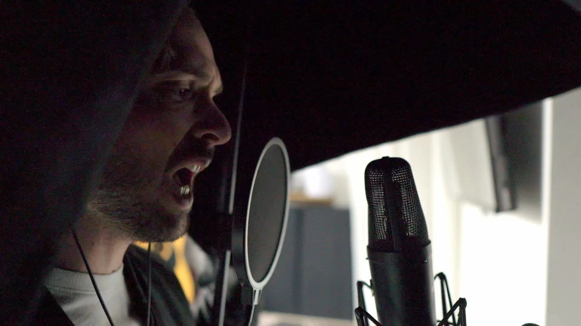 Close-up of Mattie singing into condenser microphone during vocal recording session, demonstrating proper vocal technique before pitch correction